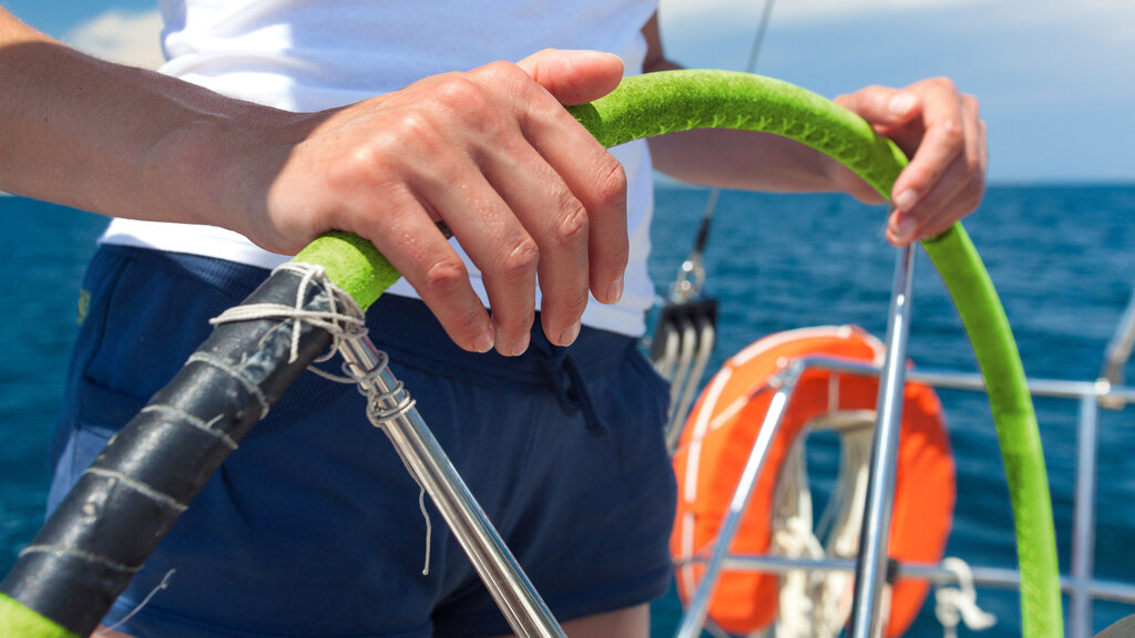 Eine Seglerin hält das Steuerruder in der Hand
